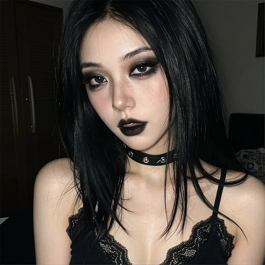 Black-haired woman with dark lipstick and leather choker in a black lace camisole in a dim bedroom